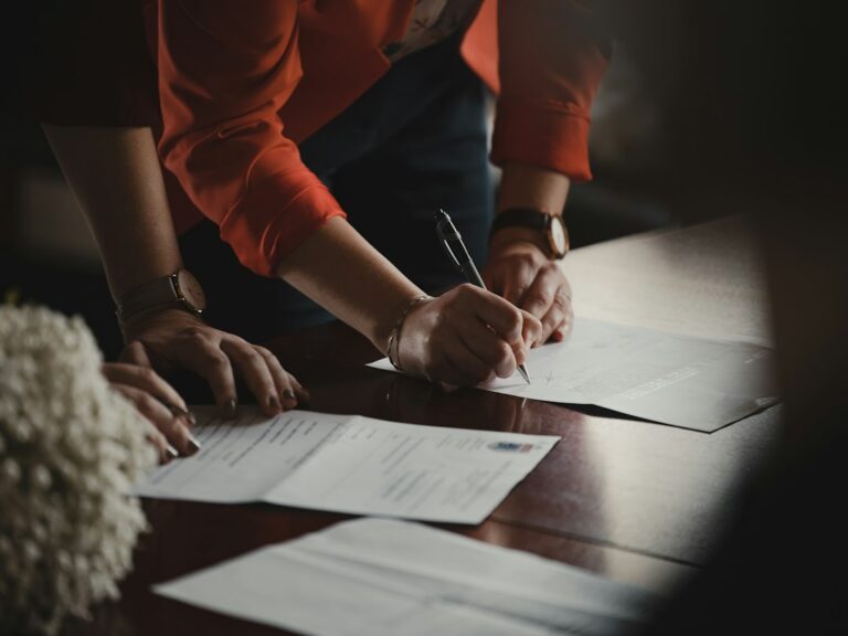 Business owners review a lawsuit packet, contract files, and a calendar at an office table.